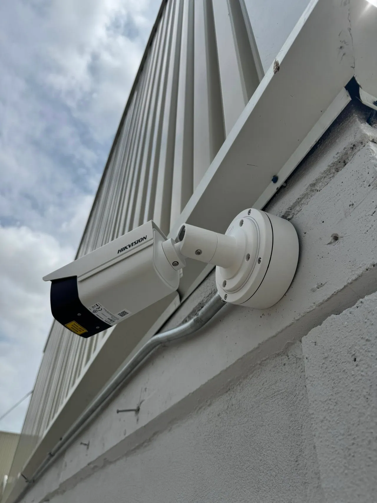 Cámara de seguridad Hikvision instalada en la fachada de una nave industrial