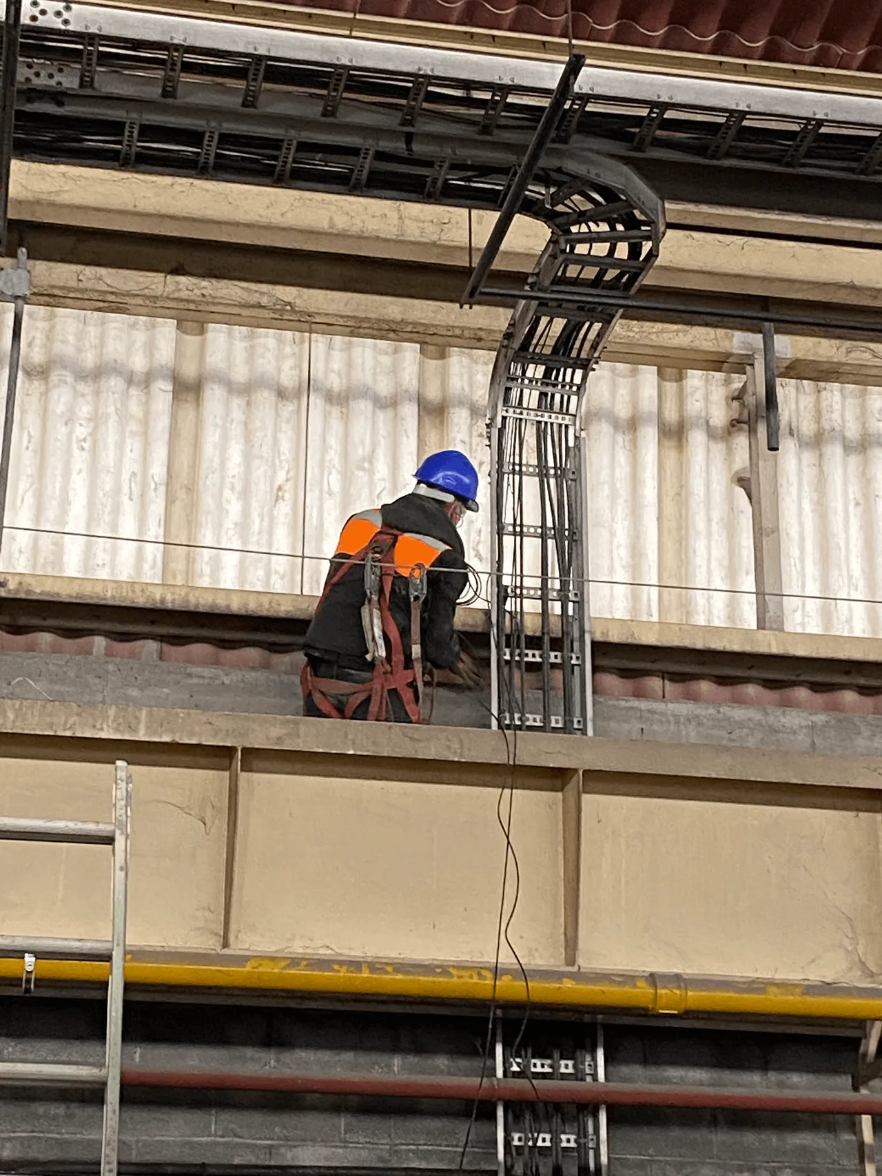 Técnico trabajando sobre una escalerilla portacables con el troncal de comunicaciones de una planta